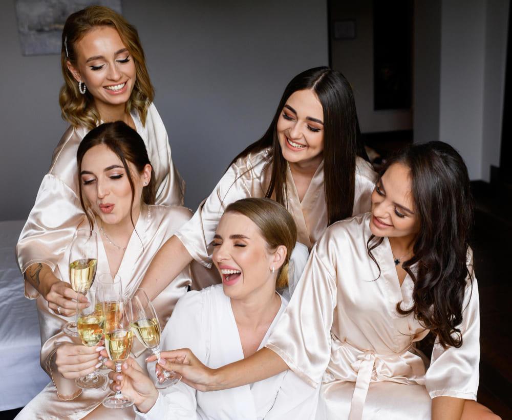 Photo of smiling women in bathrobes holding a glass of wine.